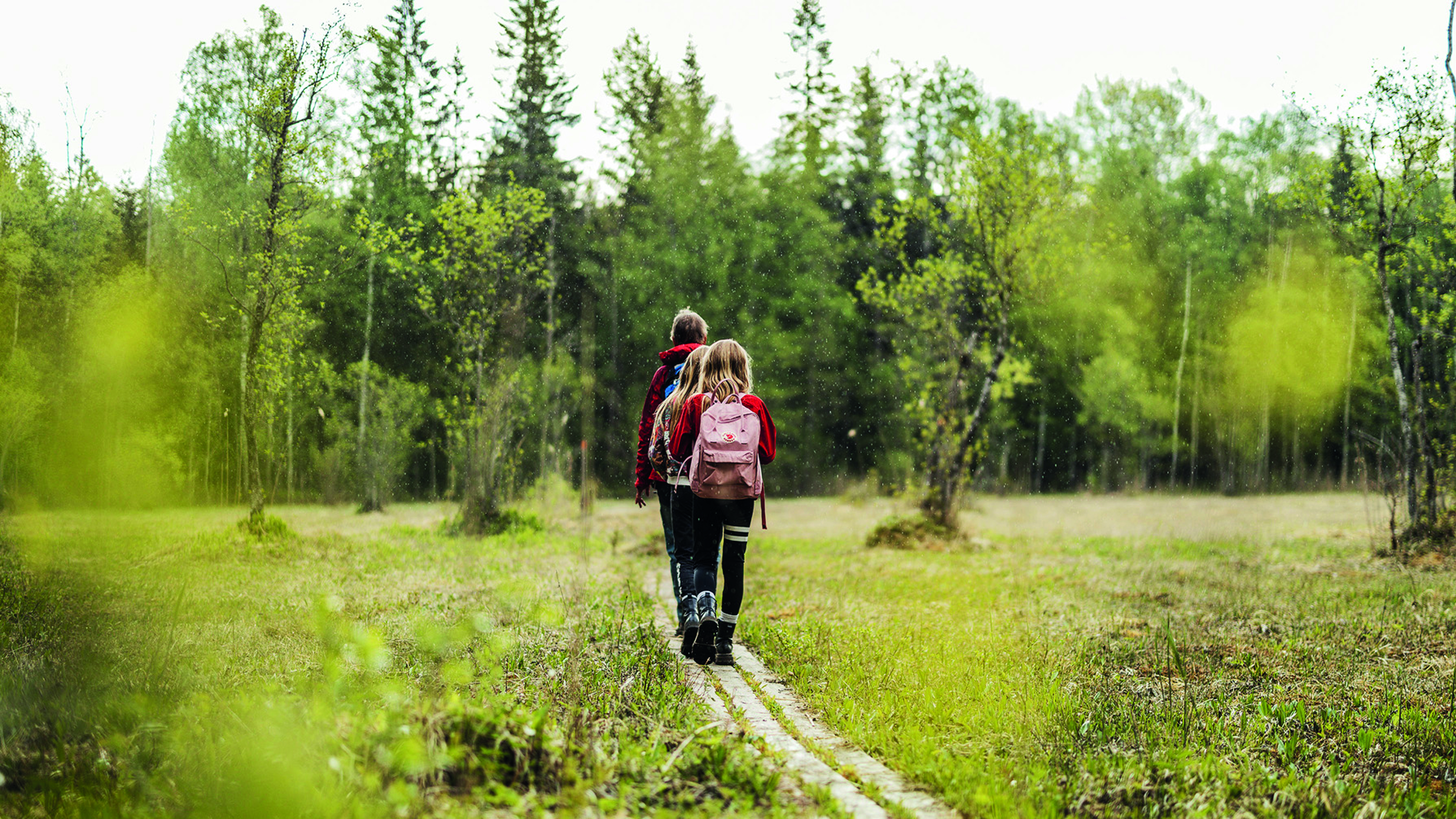Två barn och en vuxen kvinna som vandrar i Leja naturreservat